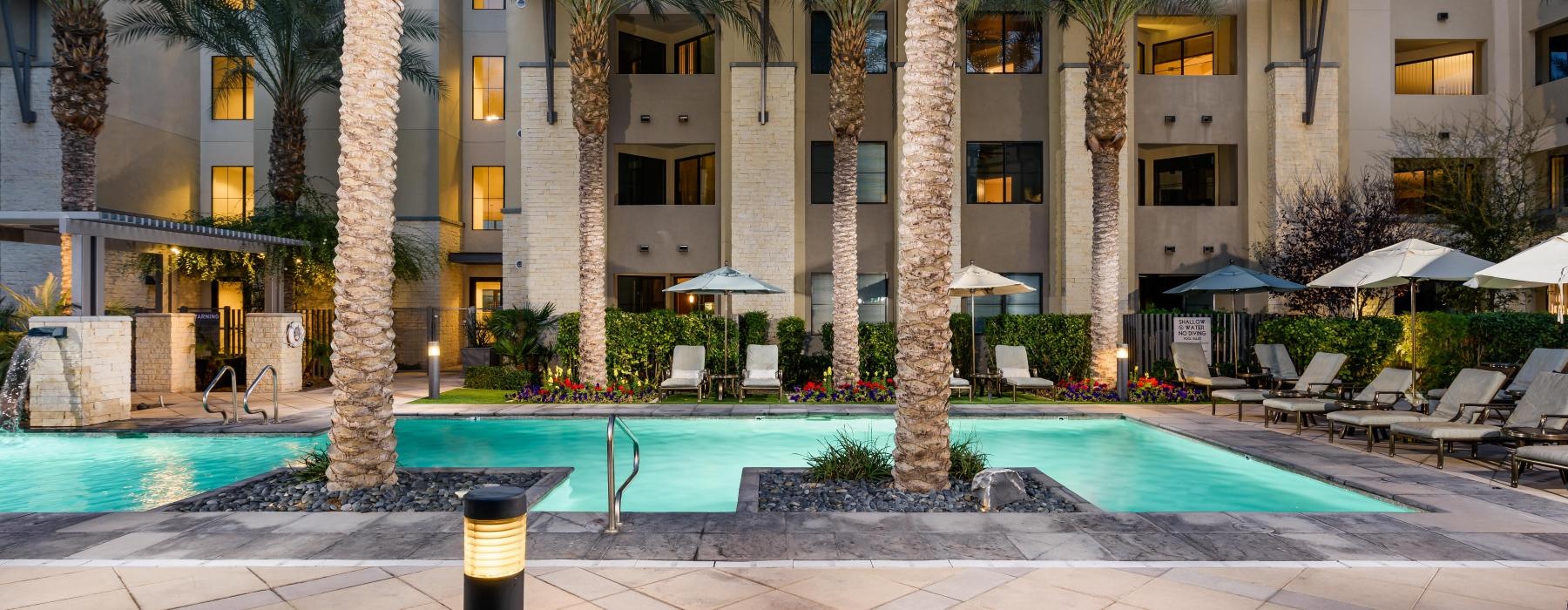 a pool with palm trees and a building in the background