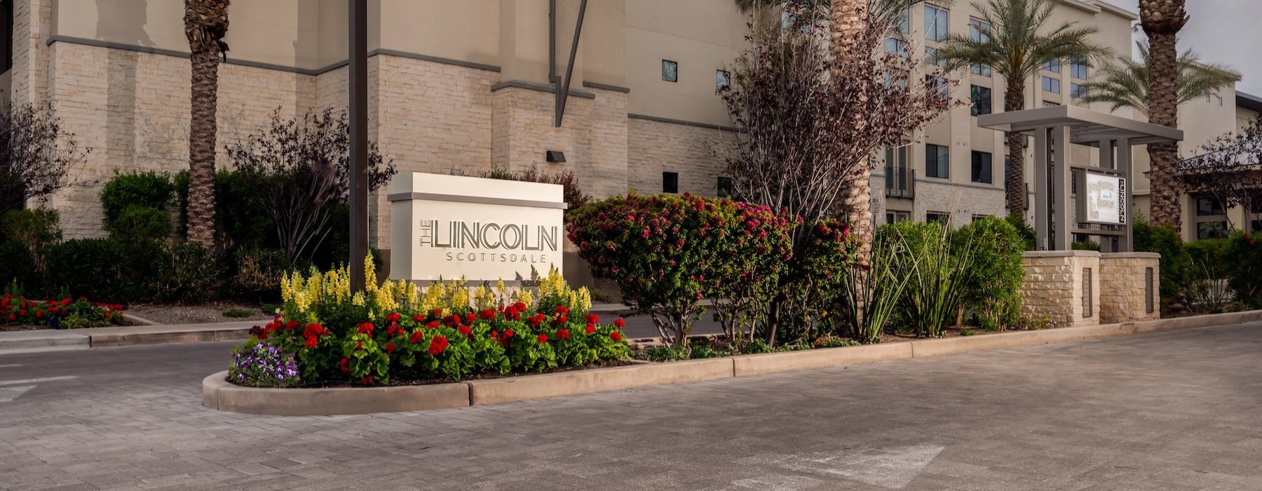 entrance to a property with a sign and landscaping around it