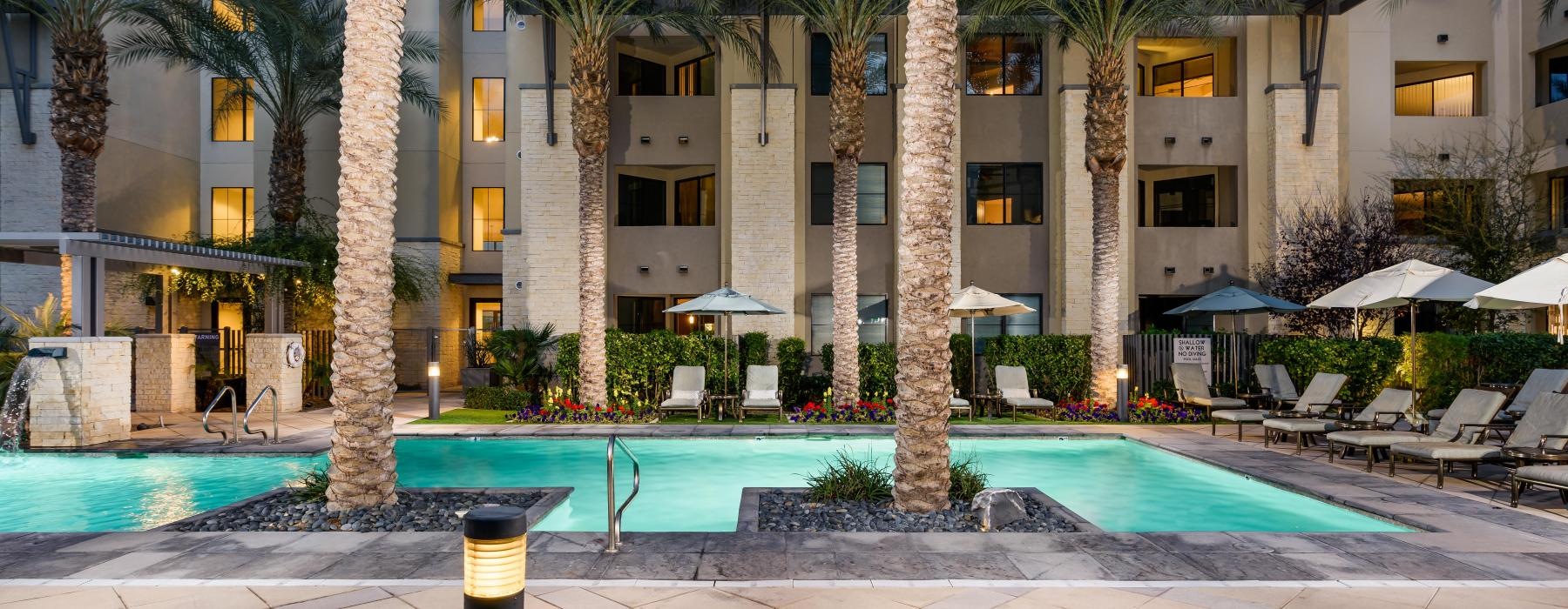 a pool with palm trees and a building in the background